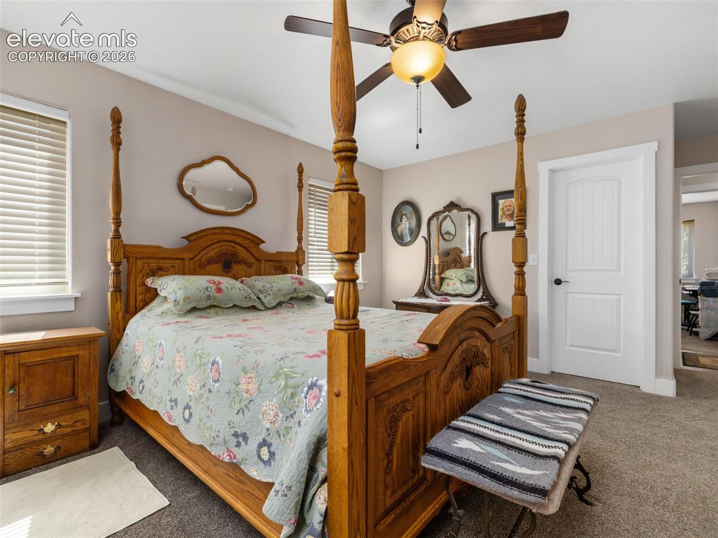 Window with blinds, ceiling fan with light fixture, paneled interior door, and carpet flooring