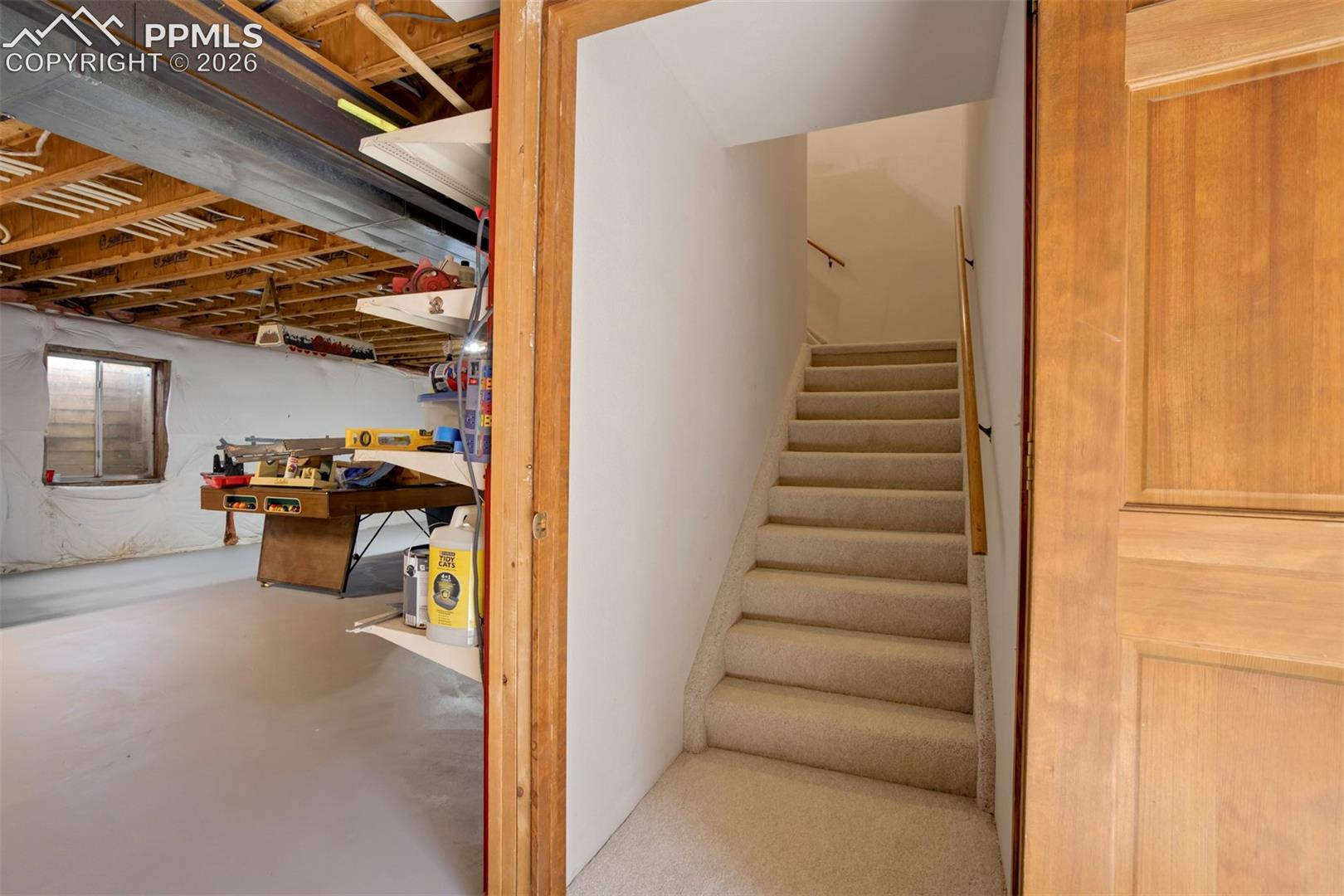 Carpeted staircase with wooden handrail, leading to an upper level