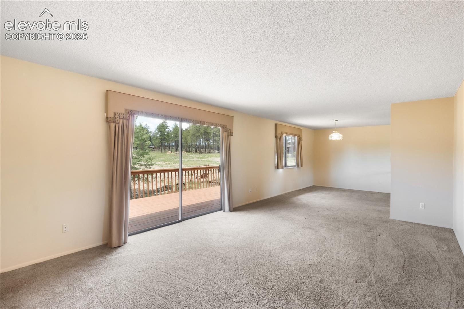 Living room with door to the deck, dining area at the back