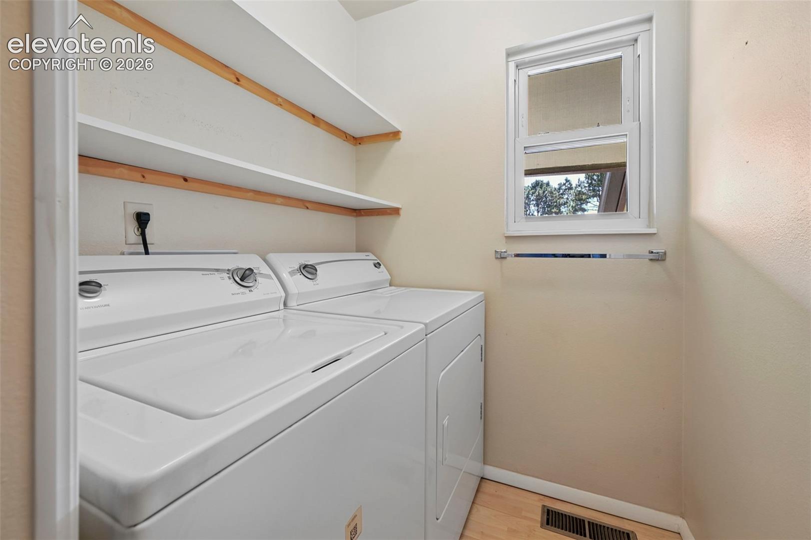 Laundry area featuring wood-finish flooring and multiple built-in shelves