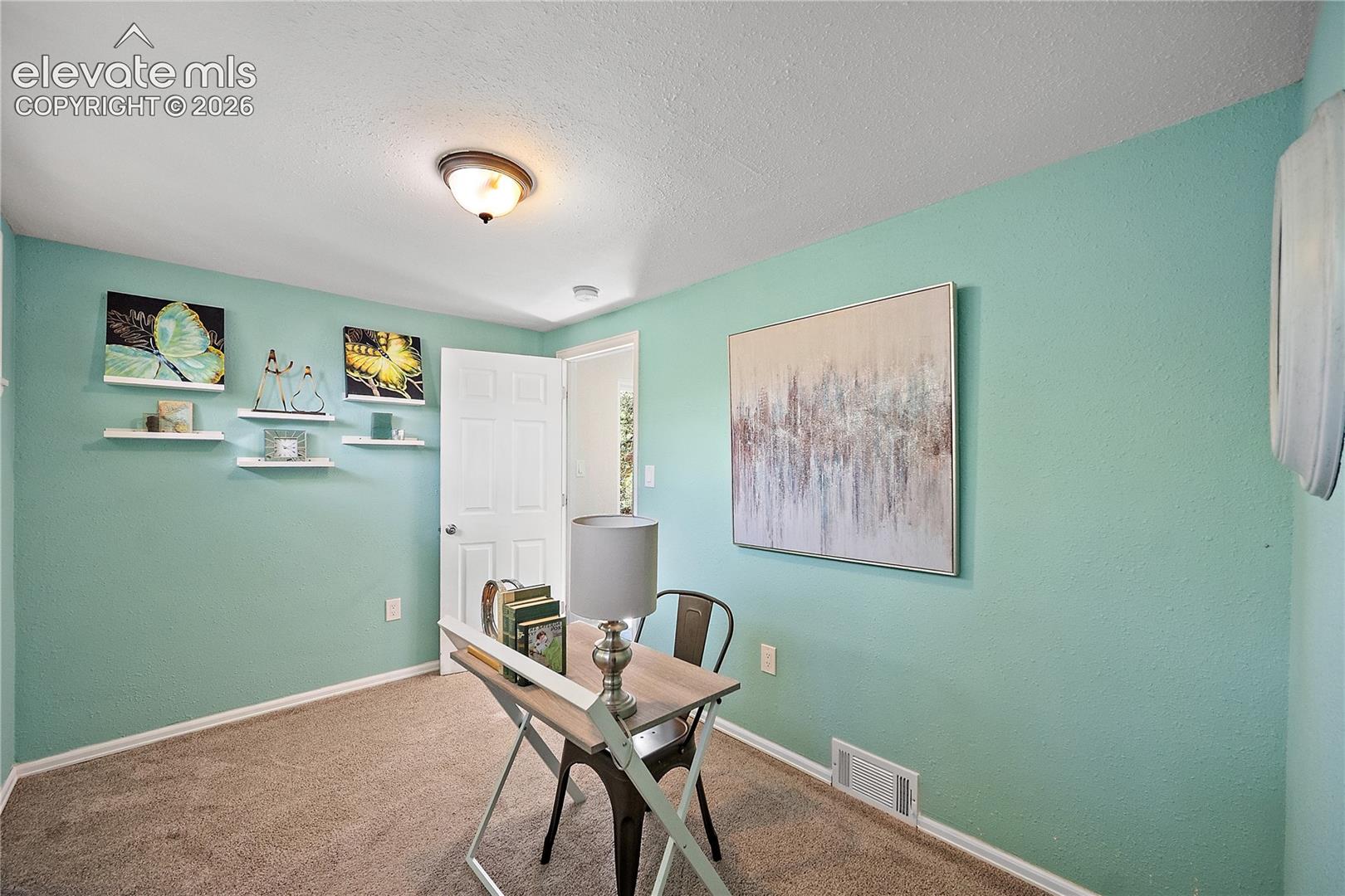 Interior room featuring light blue walls, brown carpeting, a white paneled door, and a flush-mount ceiling light fixture
