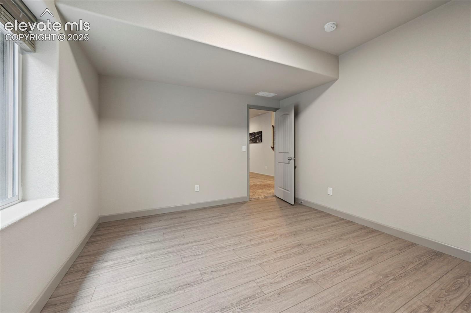 Interior space featuring neutral wall paint, wood-finish flooring, and a single-panel interior door