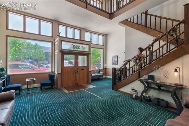 Foyer entrance with a high ceiling, stairway, a baseboard radiator, and carpet