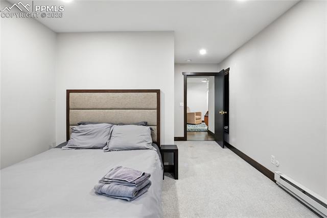 Bedroom with baseboard heating, light colored carpet, and recessed lighting