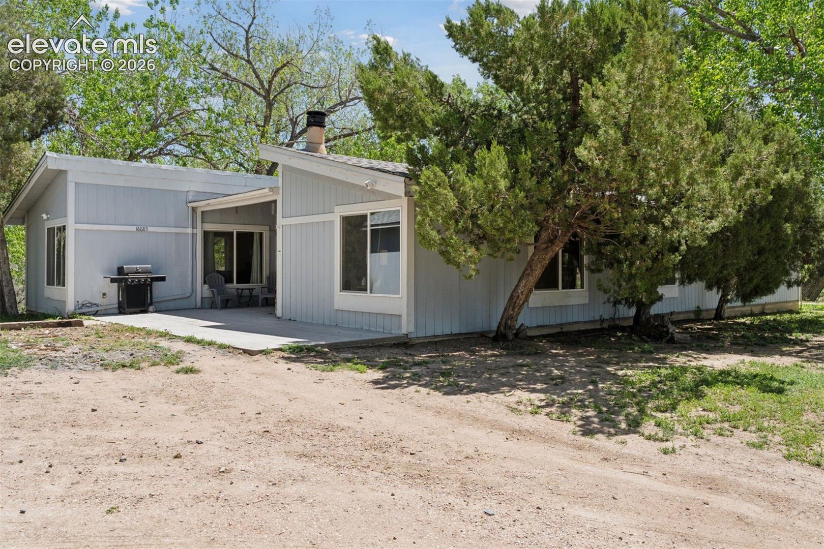 Additional exterior view of the primary single-family residence with covered patio and mature trees.
