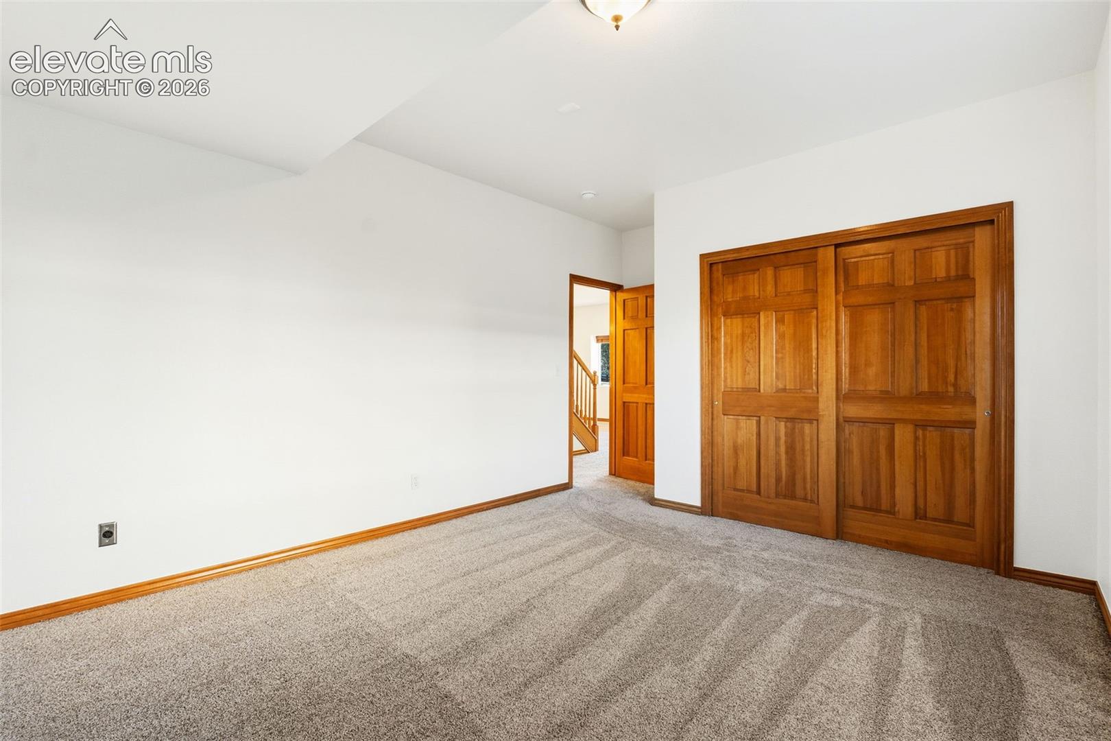 Interior space featuring neutral wall-to-wall carpeting, wood-finish sliding closet doors, and wood-finish interior doors