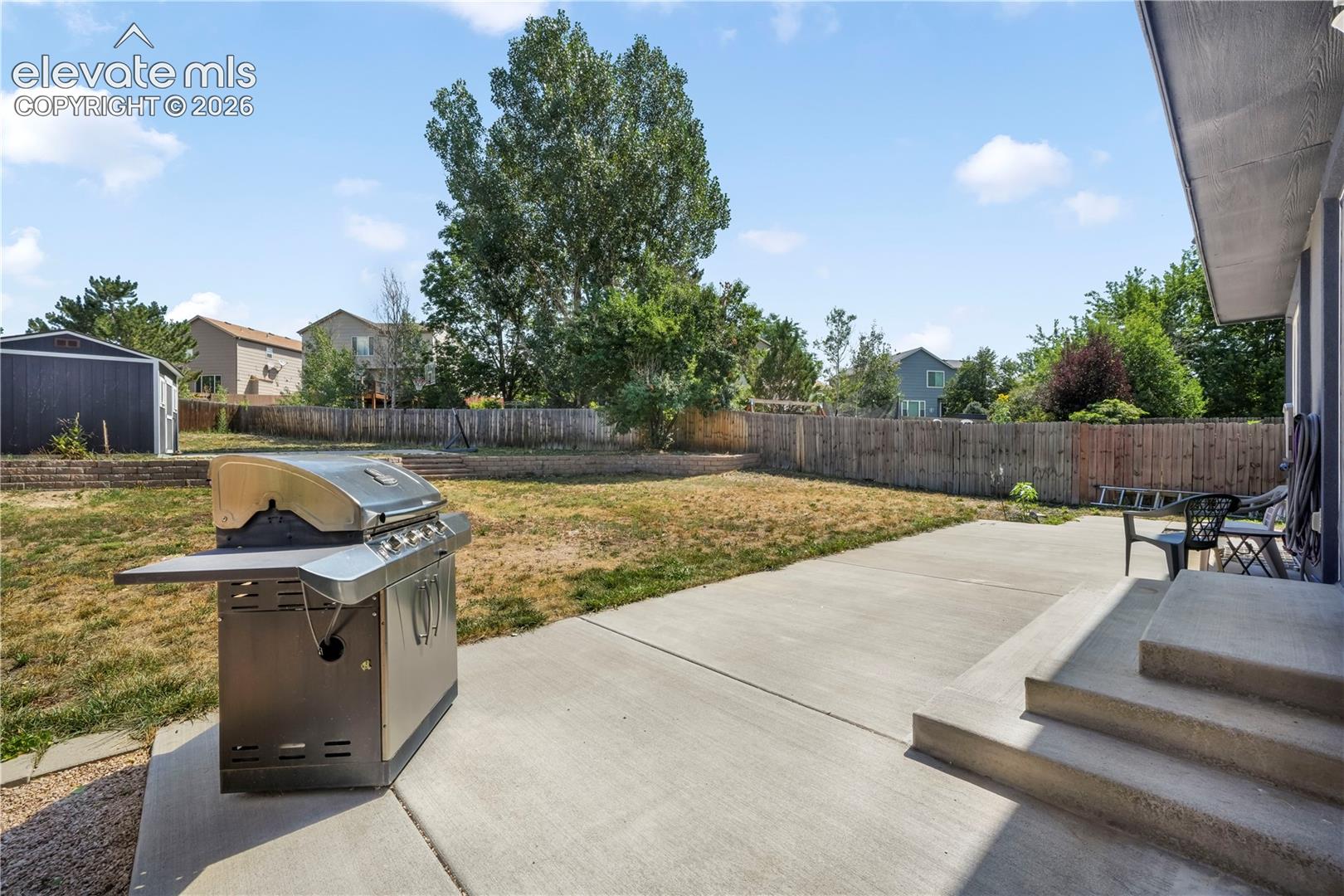 Back of home with large backyard patio, multiple levels, basketball goal and shed for storage