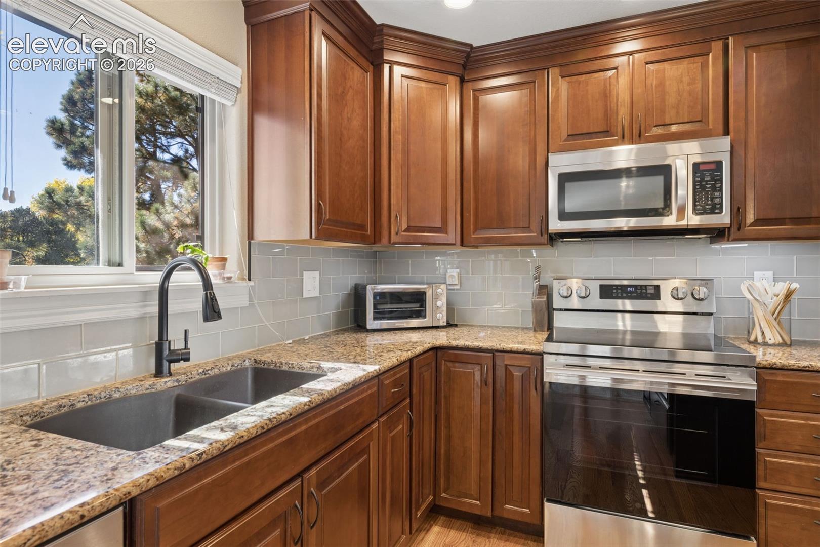 Updated kitchen with island, stainless steel appliances, granite counters and glass subway tile backsplash