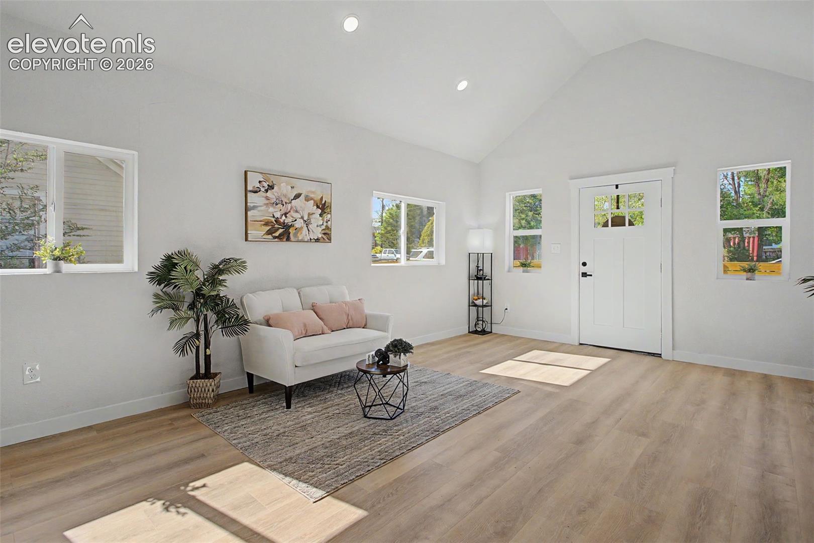 Vaulted ceiling living space with wood-finish flooring