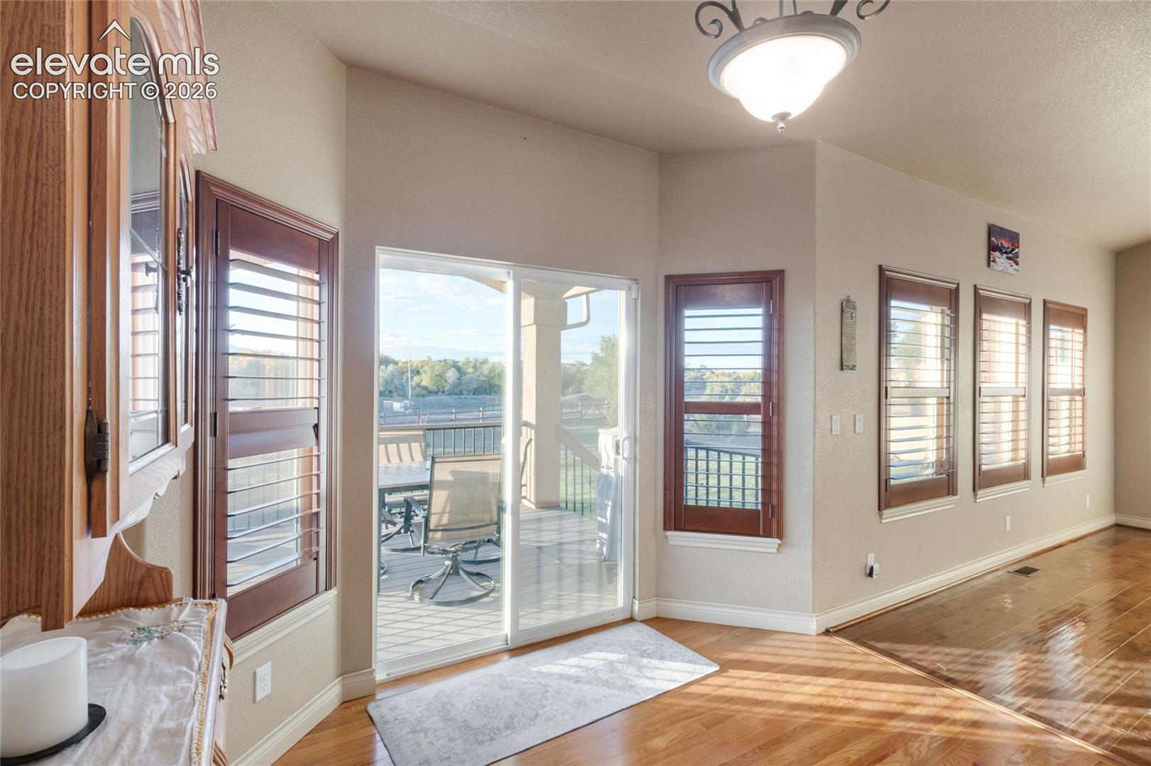 Wood-finish flooring, sliding glass door to the covered deck, plantation shutters