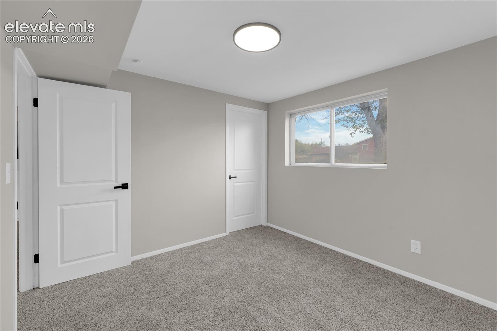 Recessed lighting, light gray wall finish, white trim, light gray carpeting, and a window with a white frame
