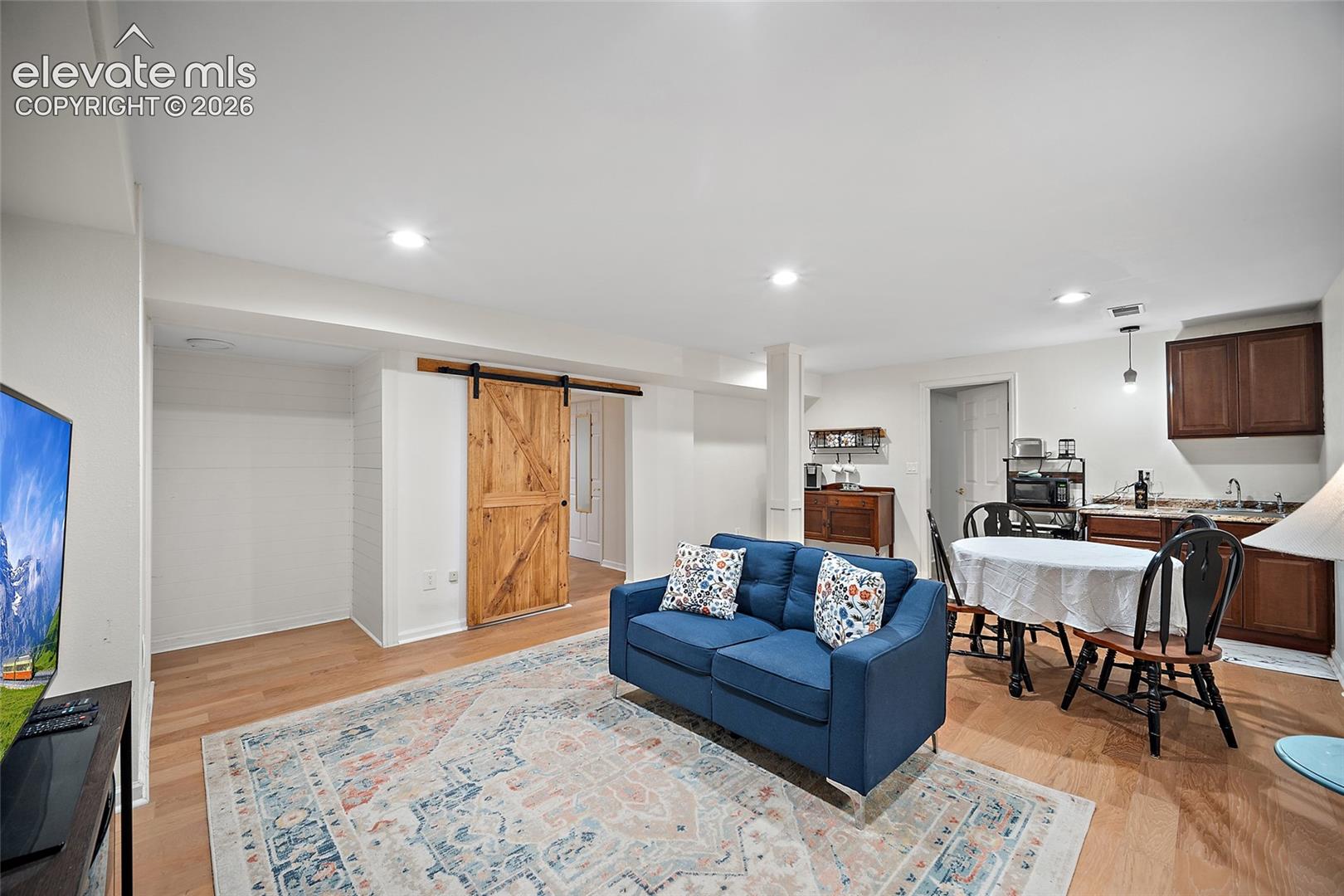 Open-concept interior featuring wood-finish flooring, recessed lighting, and a sliding wood barn door