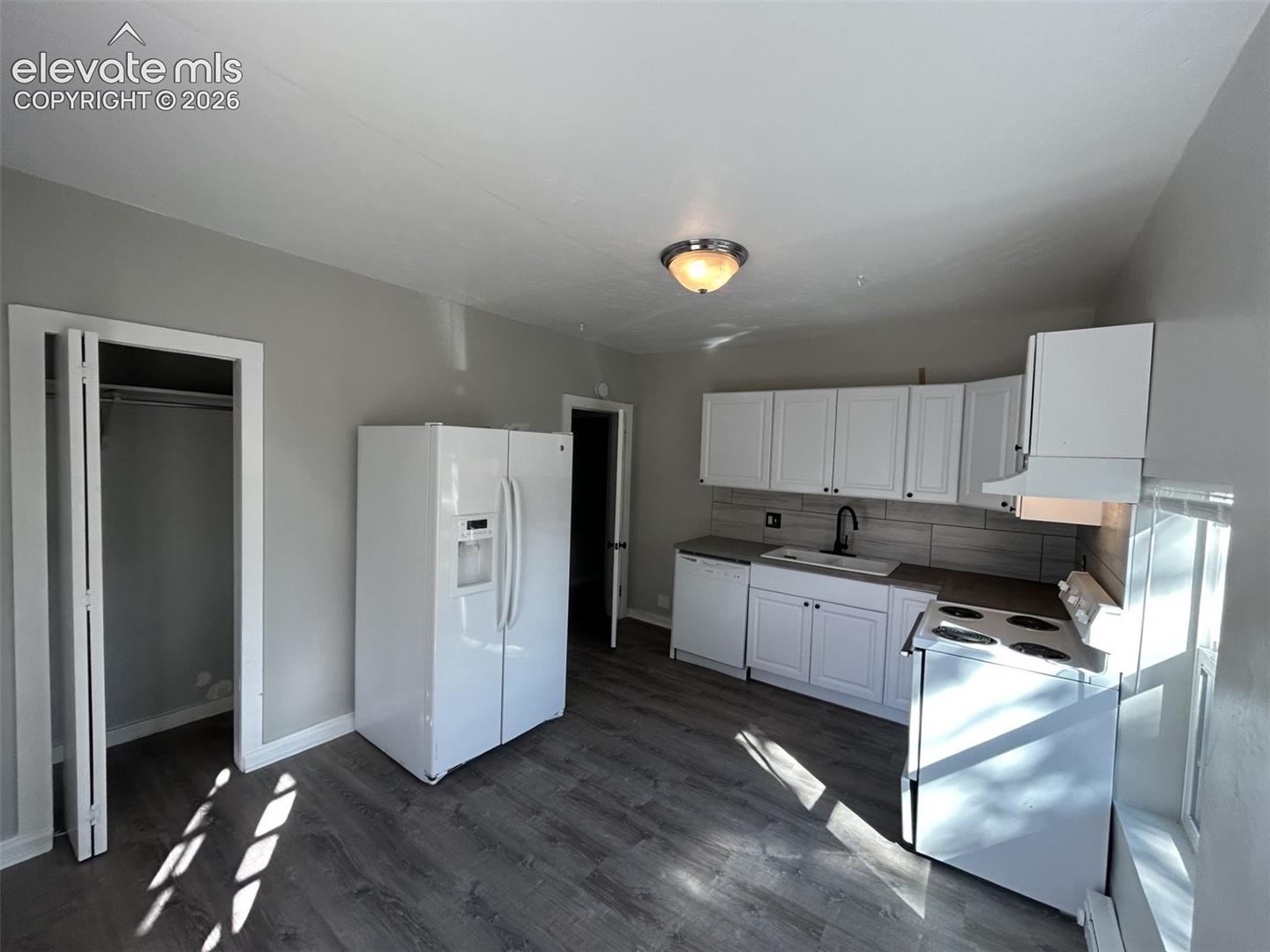 Kitchen featuring white cabinetry, gray countertops, a tile backsplash, and wood-finish flooring