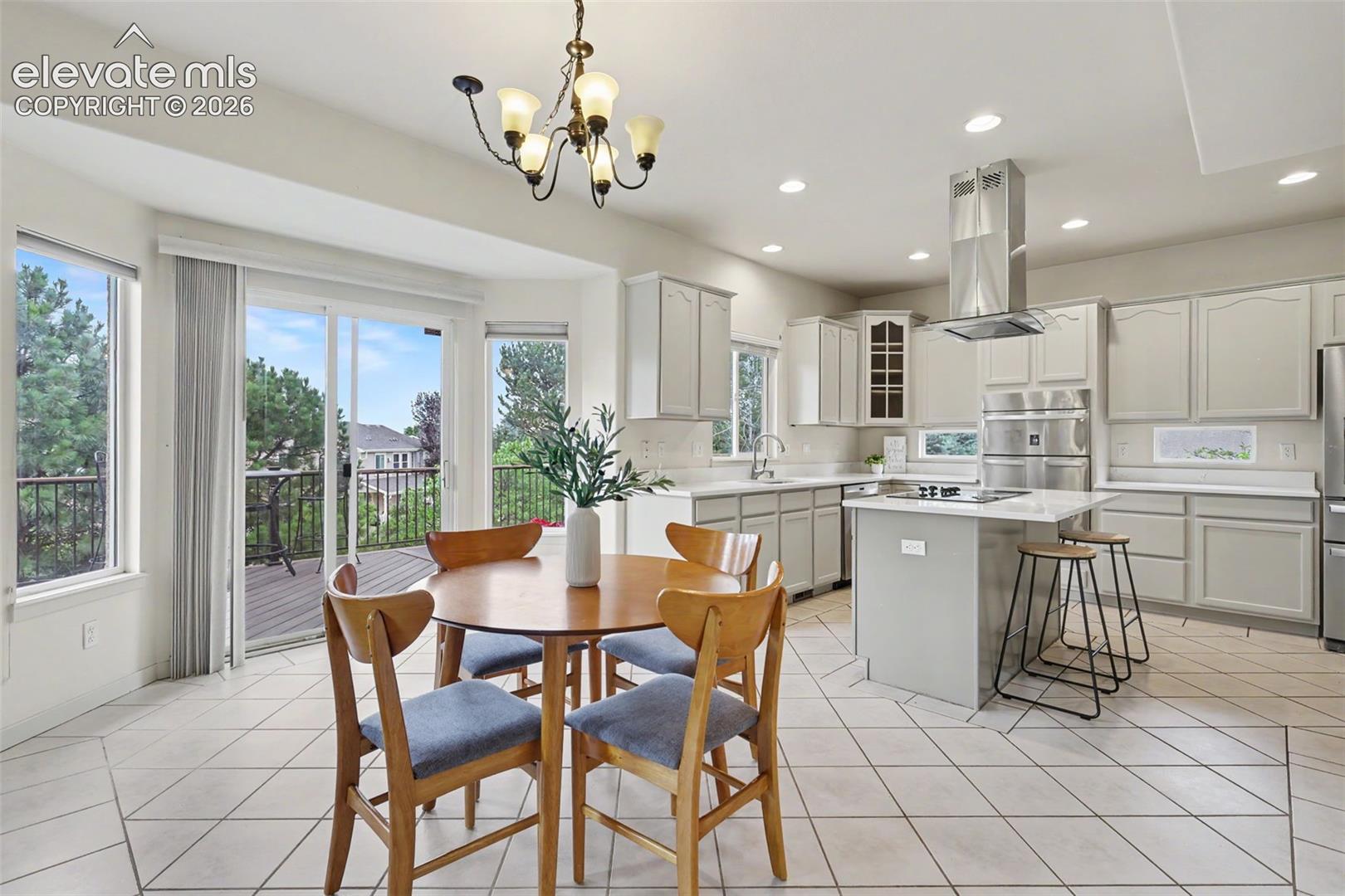 Spacious kitchen and dining area featuring white cabinetry, light countertops, stainless steel appliances, and a central island with bar seating