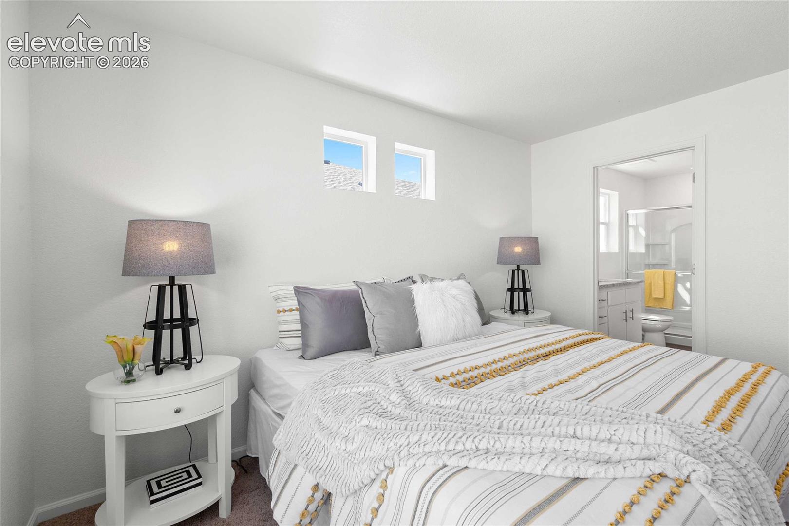 Bedroom featuring high windows and an adjacent bathroom
*photos  of a model home*