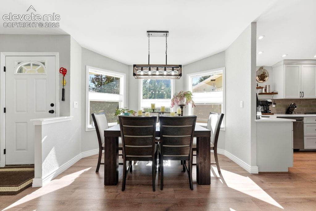 Dining area with wood-finish flooring, a contemporary chandelier, and multiple windows