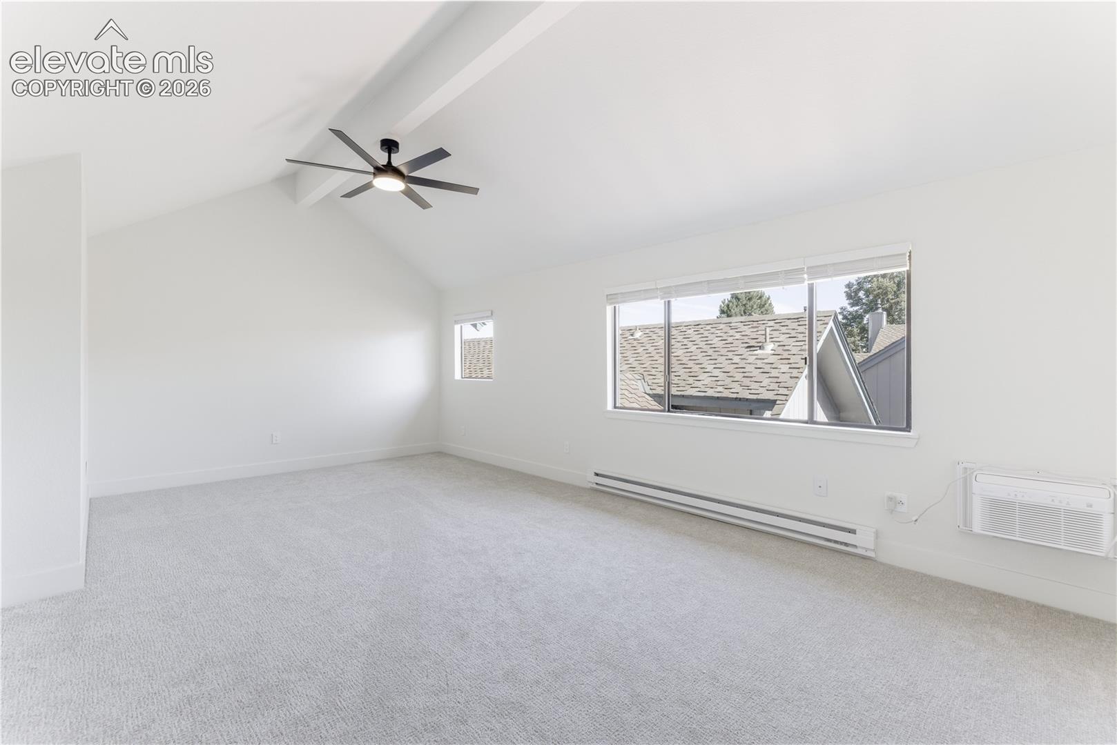 Vaulted ceilings featuring a matte black multi-blade ceiling fan, expansive windows, neutral carpeting, and a wall-mounted climate control unit