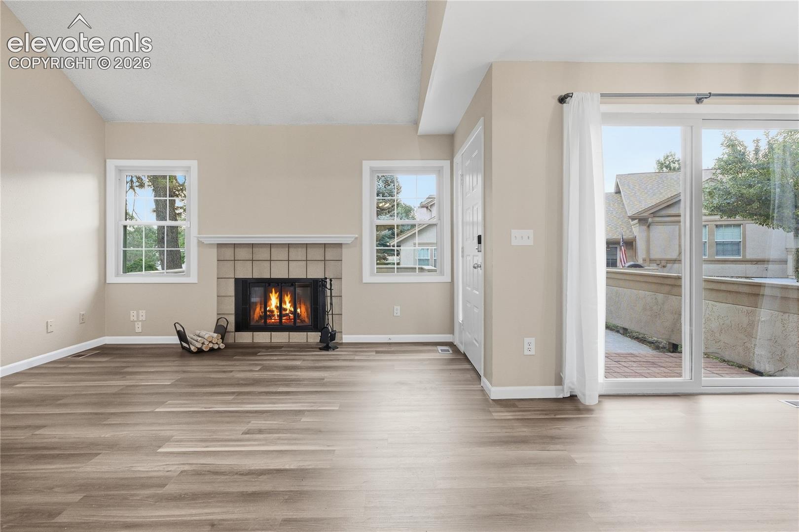 Spacious interior featuring wood-finish flooring, a tile-surround fireplace, and multiple windows