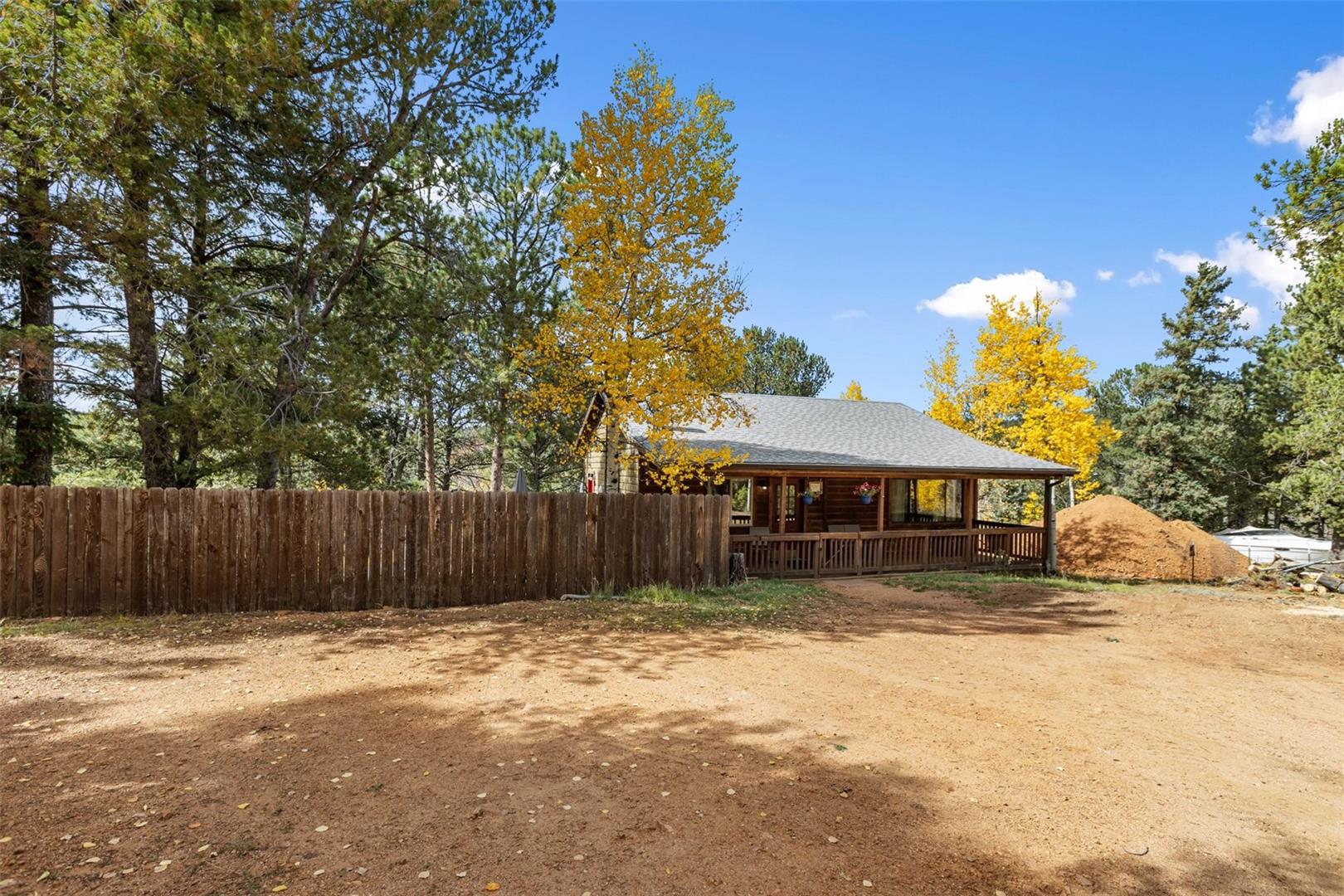 Log cabin exterior with a covered front porch, wood railing, and shingle roof