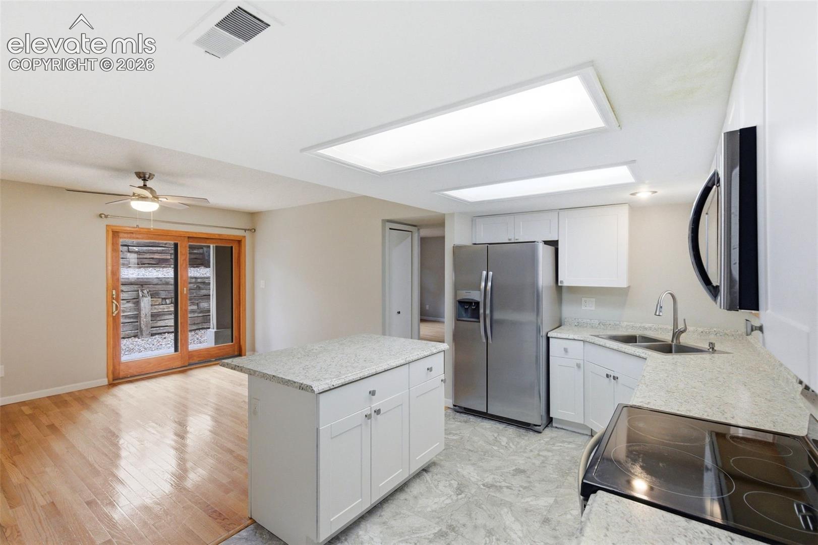 Kitchen featuring white cabinetry, light-toned countertops, stainless steel appliances, and a central island