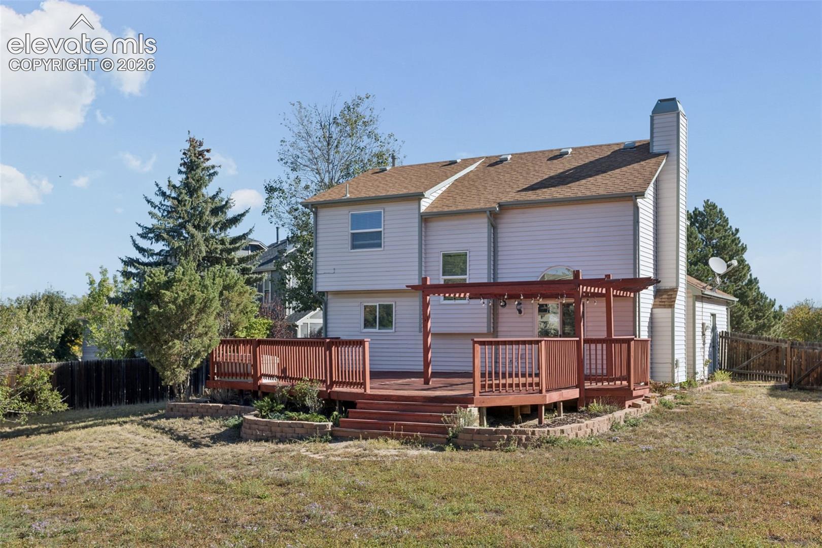 Multi-level wood deck with pergola, stone-faced retaining walls, and a wood privacy fence