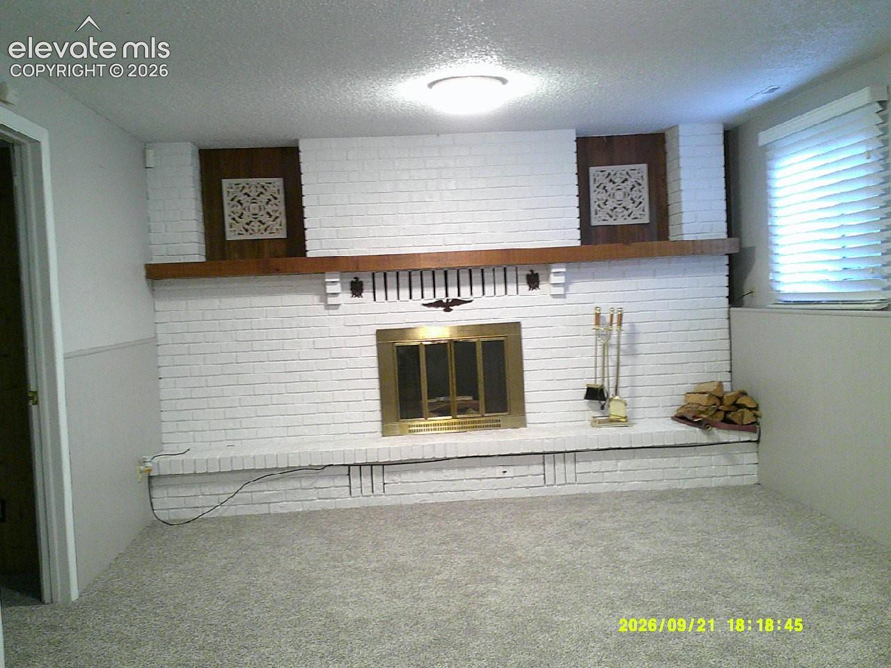 Expansive white brick fireplace with a brass firebox, a wood mantel, and integrated wood paneling