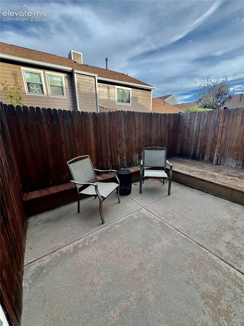 Private courtyard featuring a concrete patio, wood-finish decking, and stained wood privacy fencing