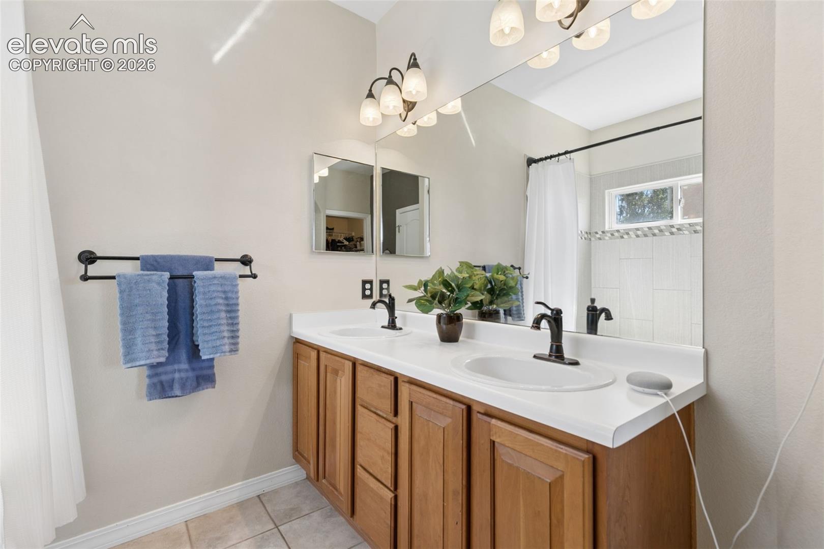 Dual vanity with white countertop, wood-finish cabinetry, and matte black fixtures