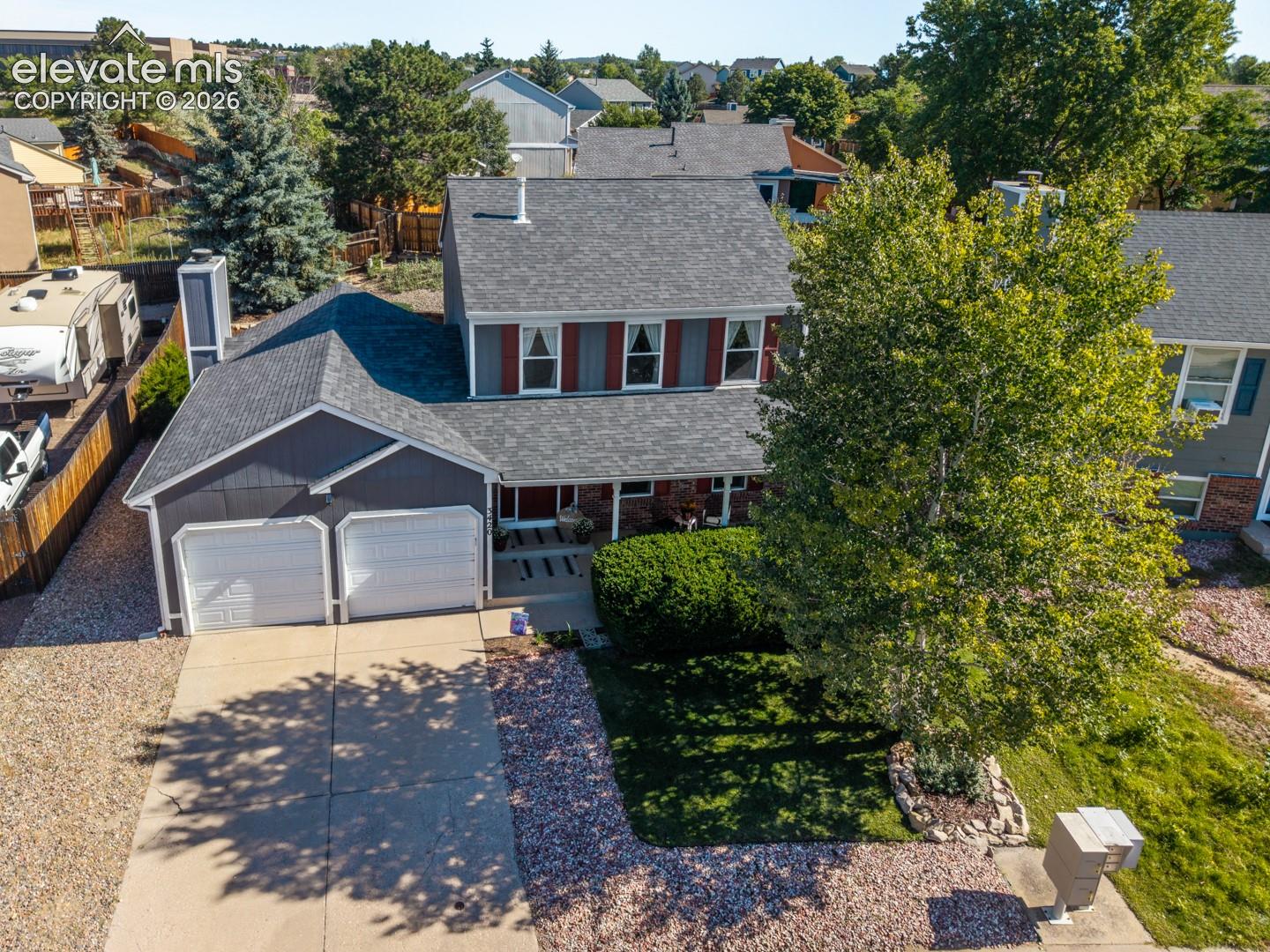 Two-car garage, concrete driveway, and mature landscaping