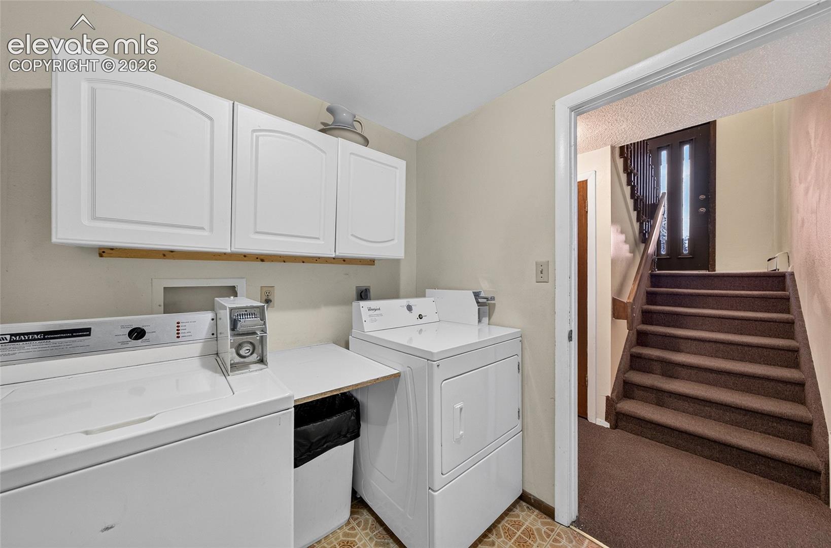 Laundry space featuring white wall-mounted cabinetry, built-in counter space, and patterned flooring