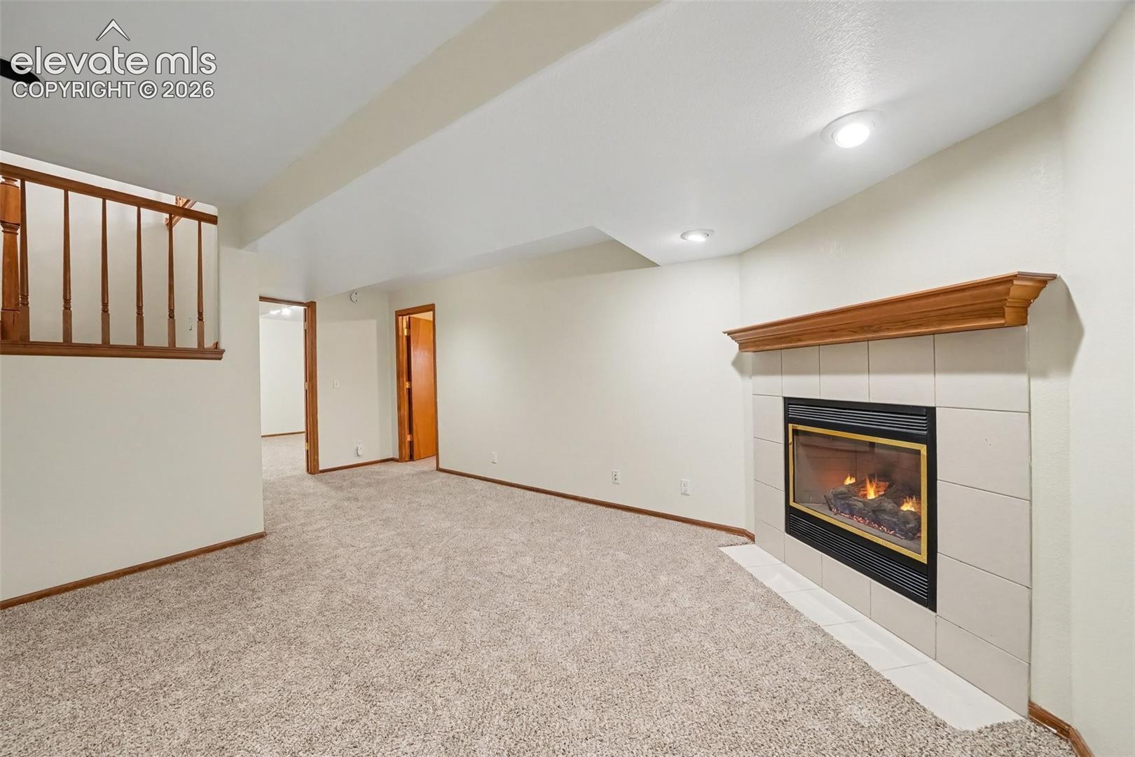 Carpeted living space with a tile-surround fireplace featuring a wood mantel