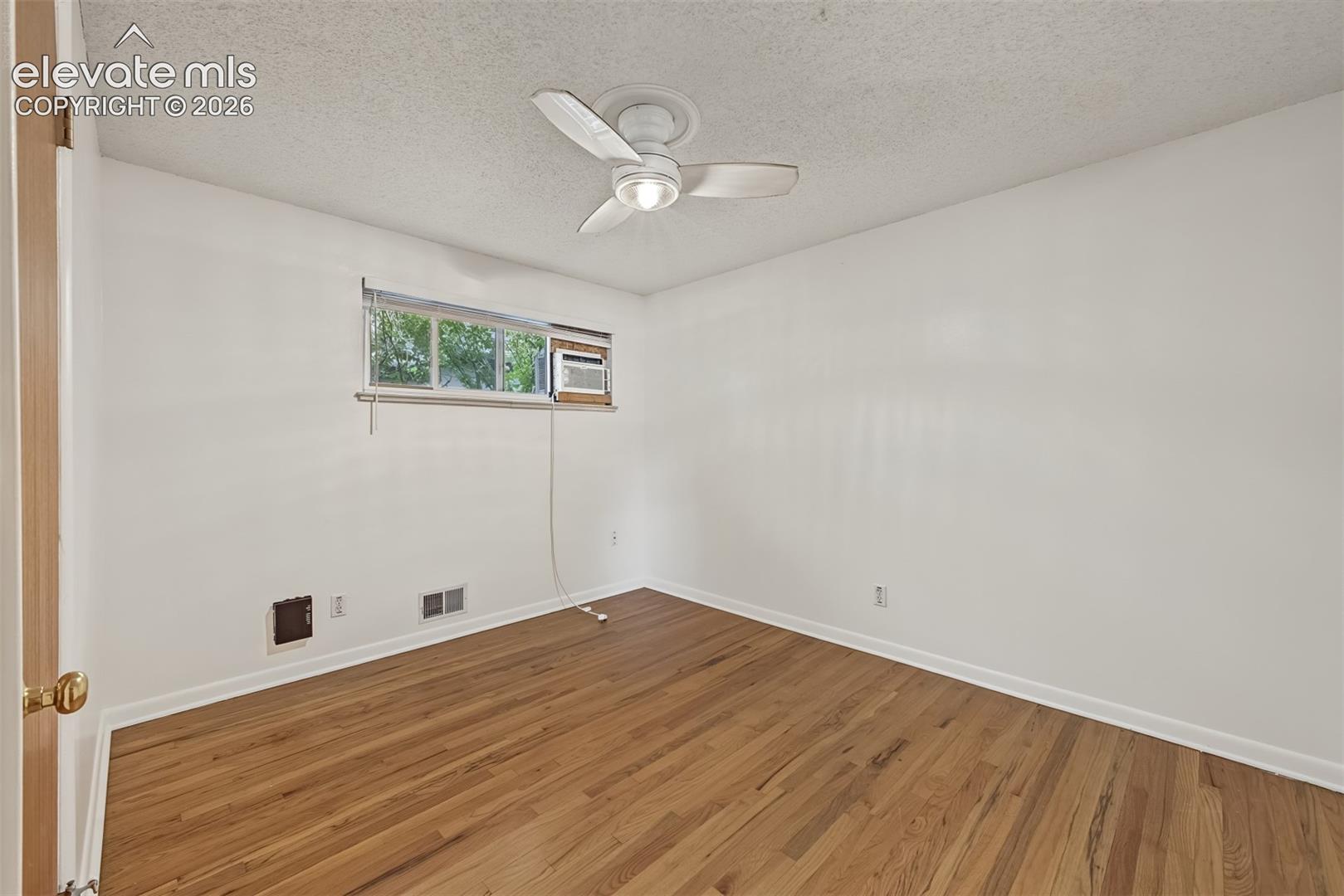 Room featuring wood-finish flooring, a ceiling fan with integrated lighting, and a horizontal sliding window