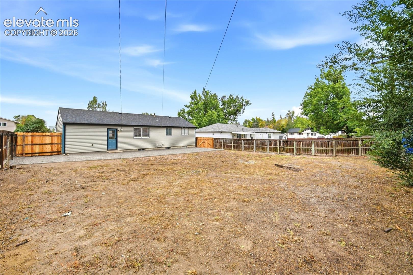 Spacious yard with fencing, gravel patio area, and exterior siding