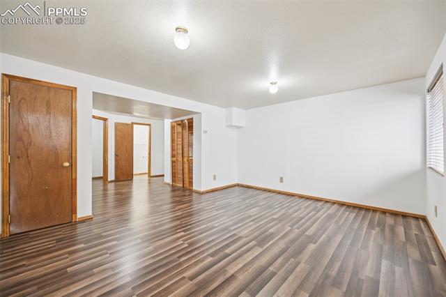 Unfurnished room featuring dark wood-style flooring and baseboards