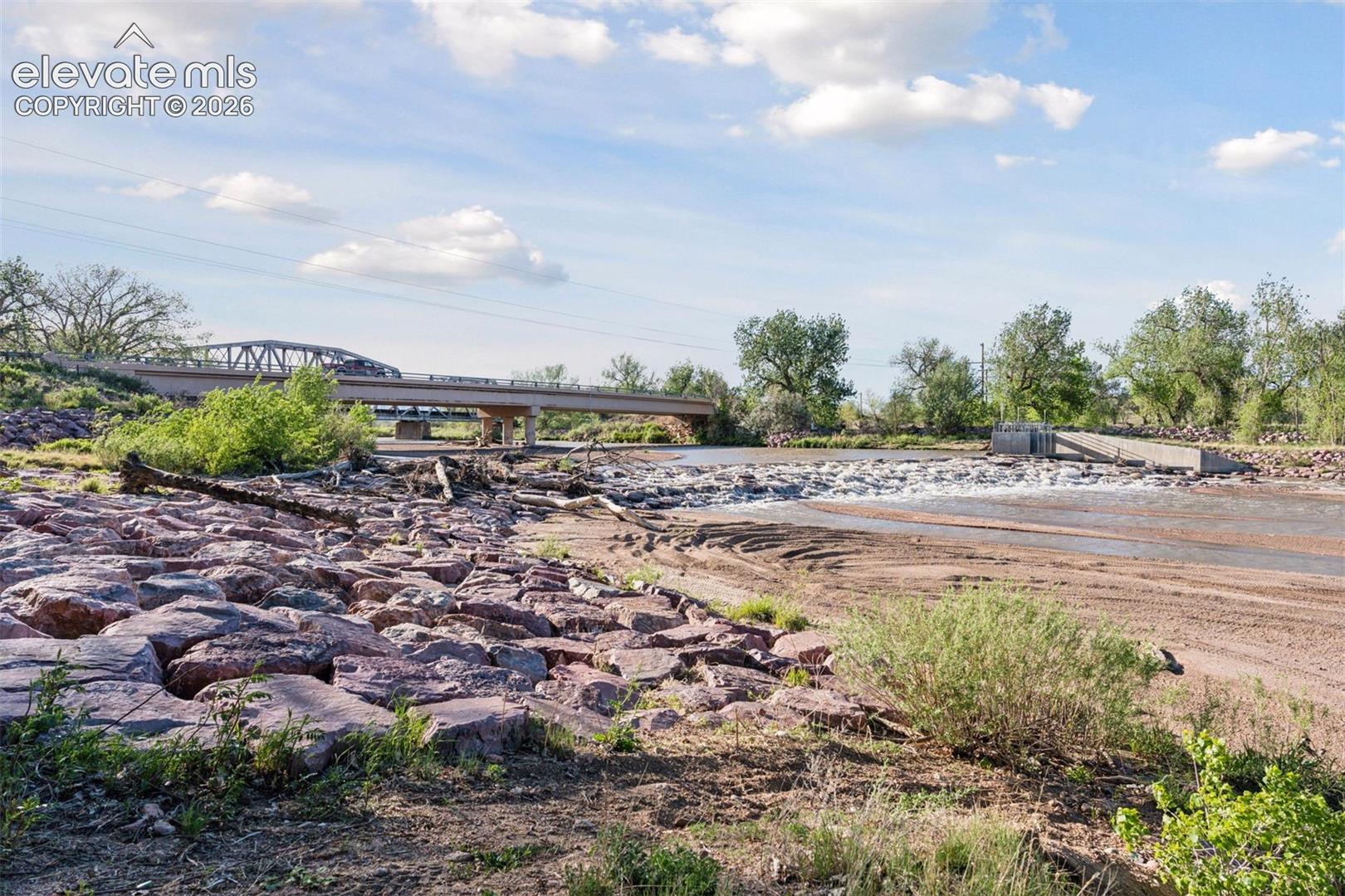 Fountain Creek corridor near Old Pueblo Road and Hanover Road, showcasing the natural riparian setting, rock-lined banks, and nearby bridge crossing