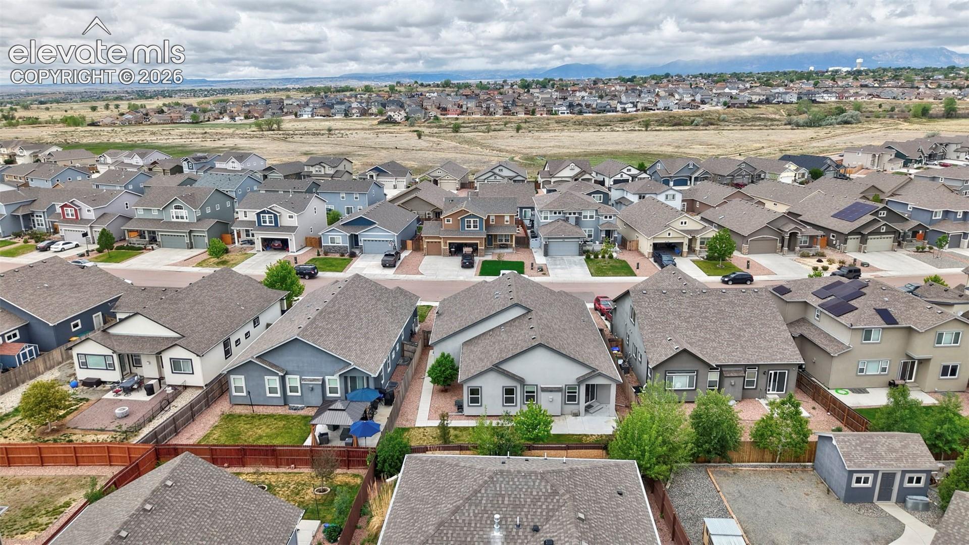 Aerial perspective of a suburban neighborhood featuring multi-story residential structures, pitched shingle roofs, integrated garages, and curated landscaping