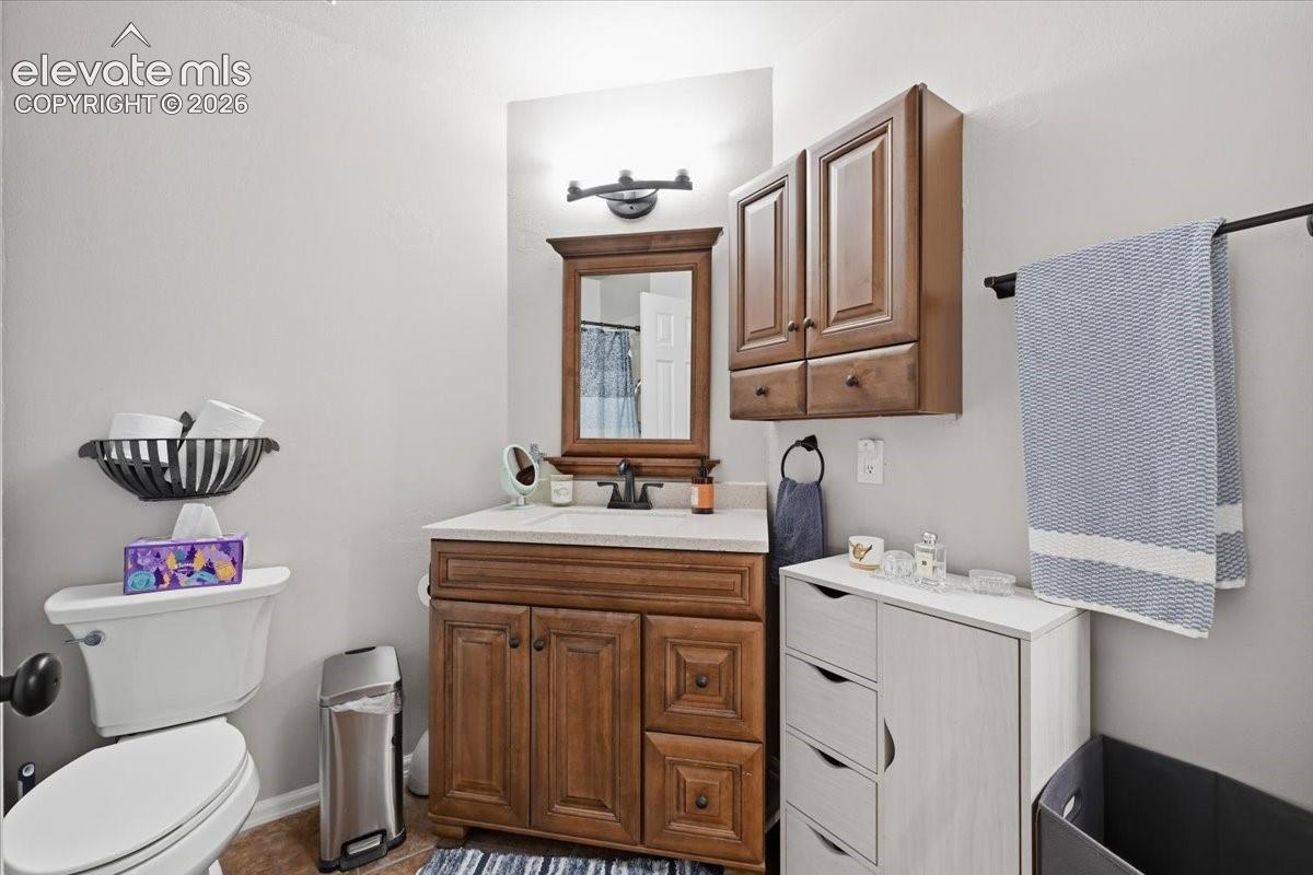 Bathroom vanity featuring raised-panel wood cabinetry, a light-toned countertop, a coordinating framed mirror, and a matching wall-mounted storage cabinet