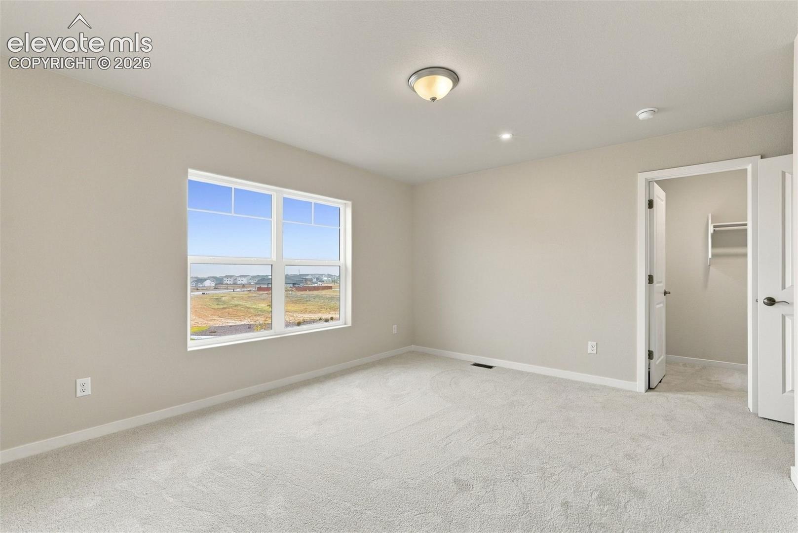 Neutral wall finishes, plush carpeting, double-pane window with grid detailing, and a built-in closet with shelving