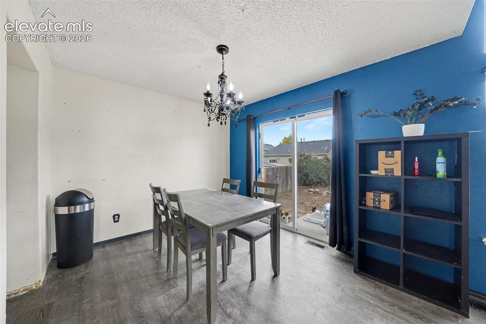 Dining area featuring wood-finish flooring, a decorative chandelier, and a sliding glass door providing external access