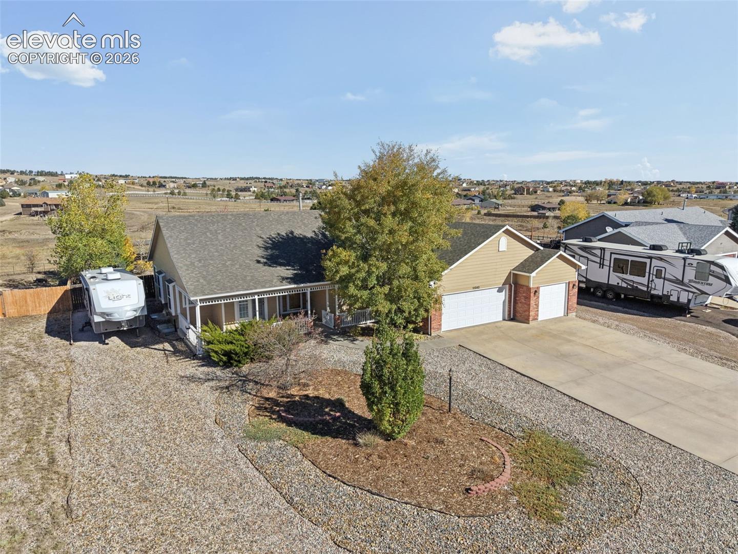Ranch-style residence featuring a multi-gabled shingle roof, lap siding, a front porch with decorative railings, a concrete driveway, and an attached two-car garage