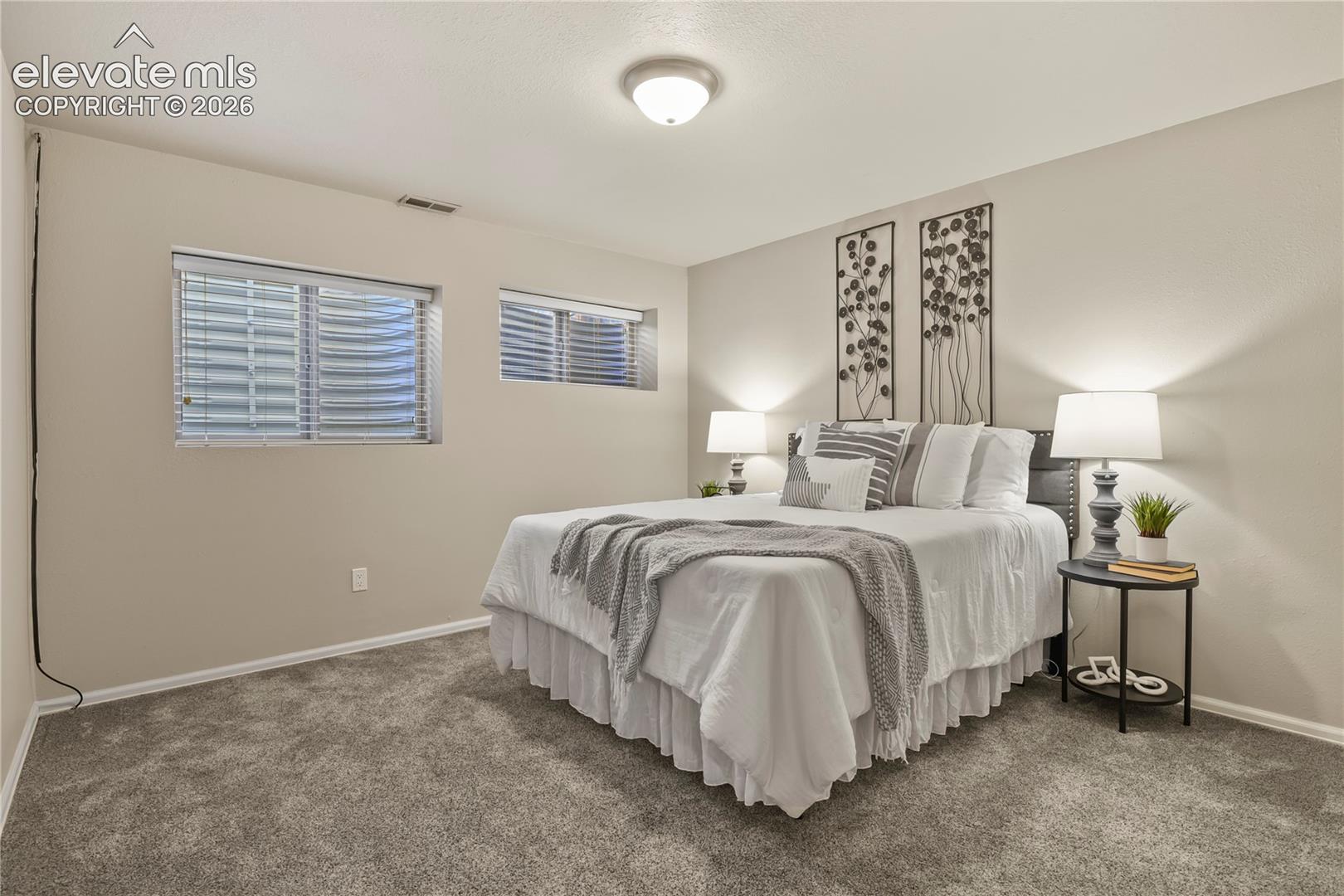 Neutral-toned interior room with wall-to-wall carpeting and two egress windows