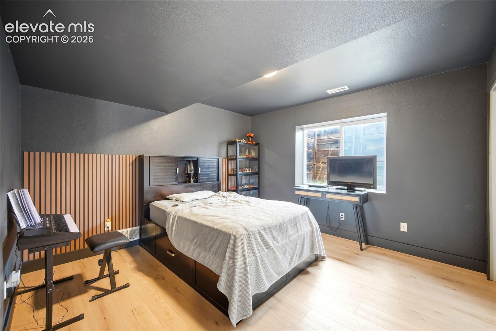 Interior space featuring wood-finish flooring, a charcoal-painted ceiling and walls, recessed lighting, and a vertical wood-slat accent wall