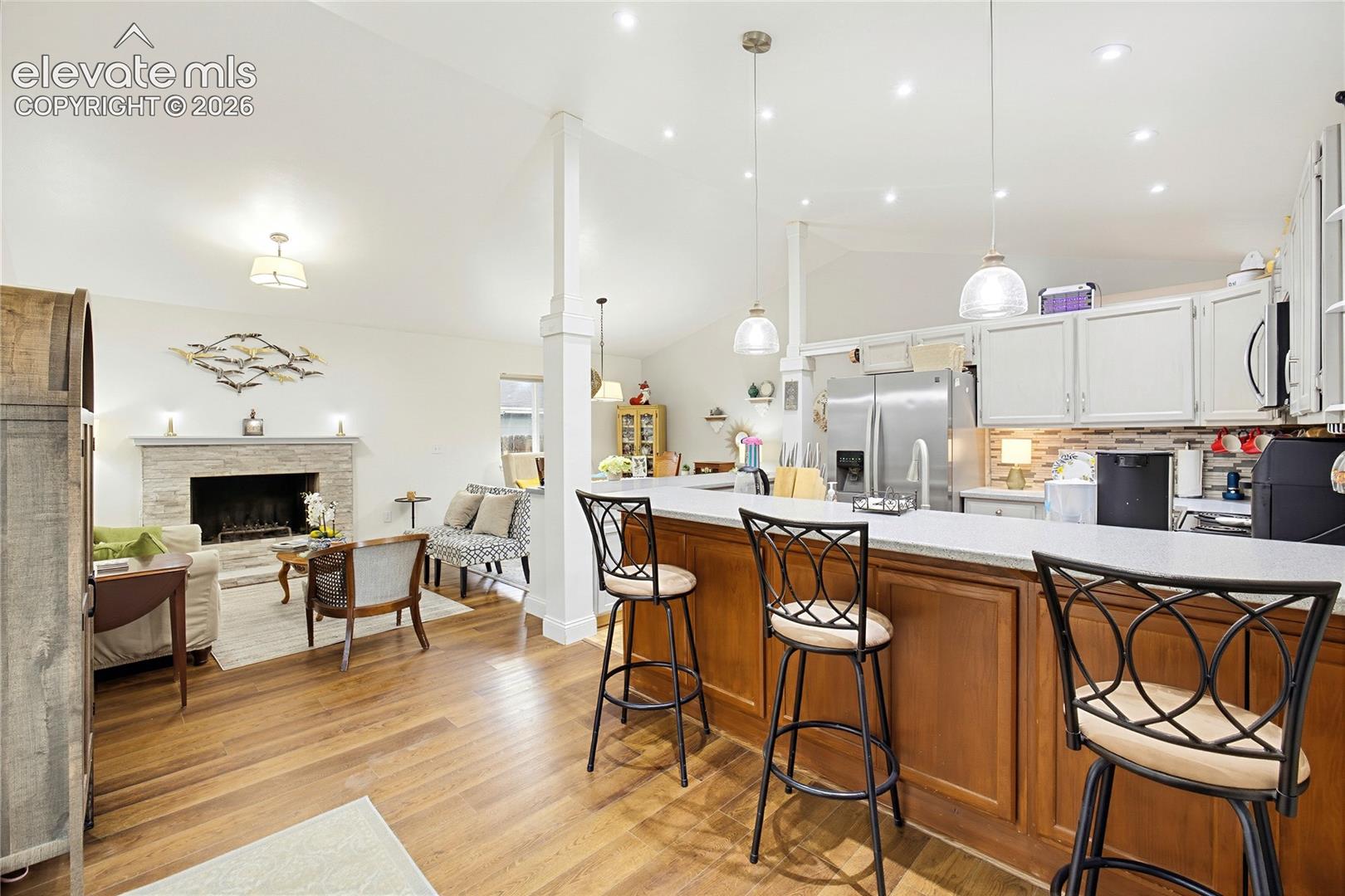 Kitchen island with stone-finish countertop, wood-finish base cabinetry, and three pendant lights