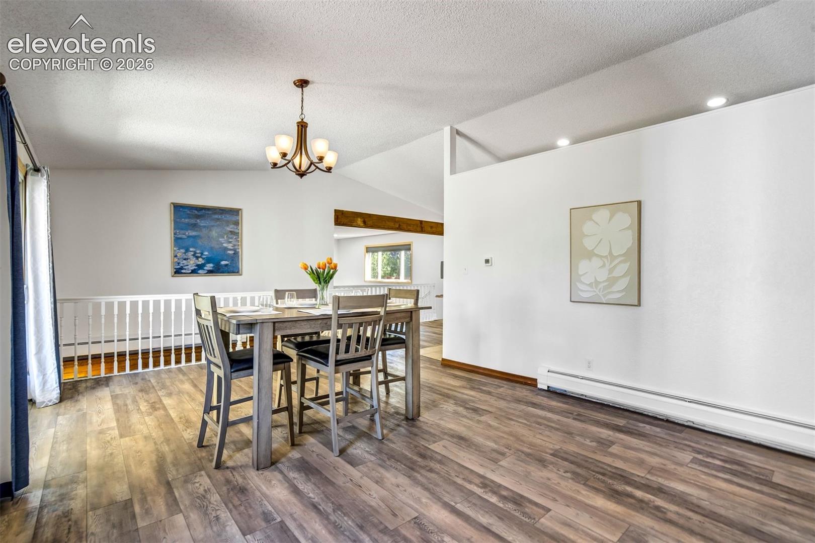 Spacious interior featuring wood-finish flooring, vaulted ceilings, and a bronze chandelier