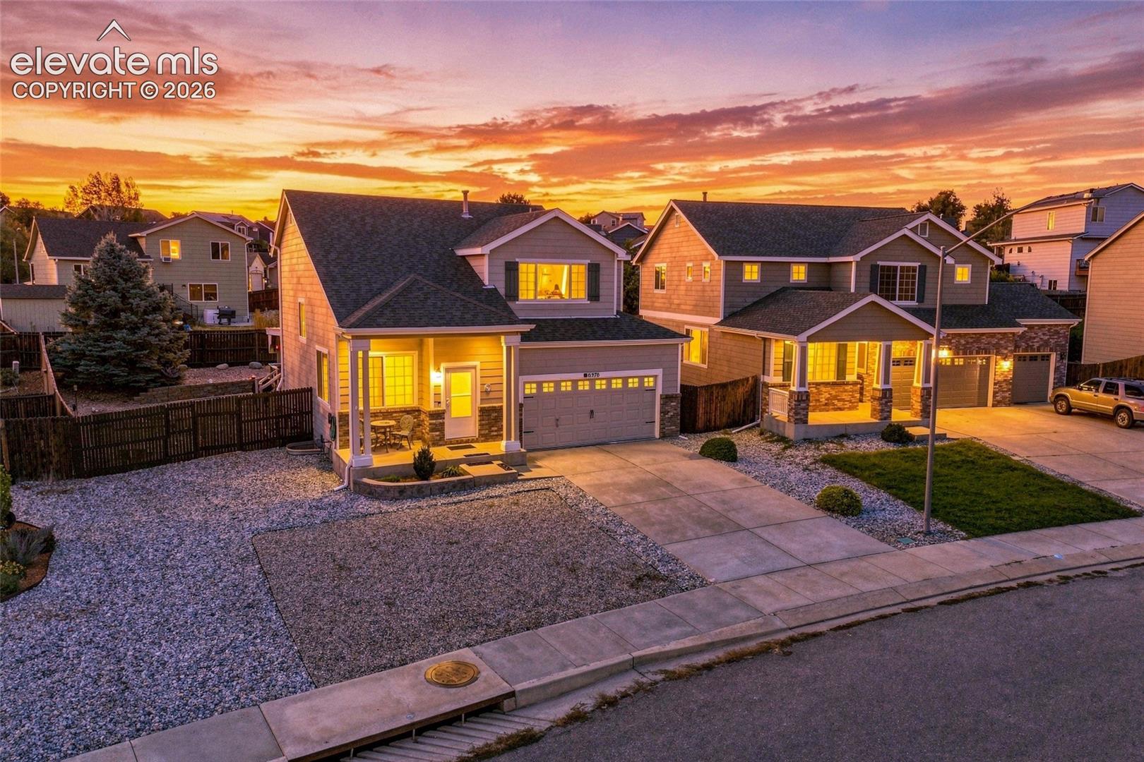 Two-story residence featuring a covered front porch, attached two-car garage, and a gravel front yard