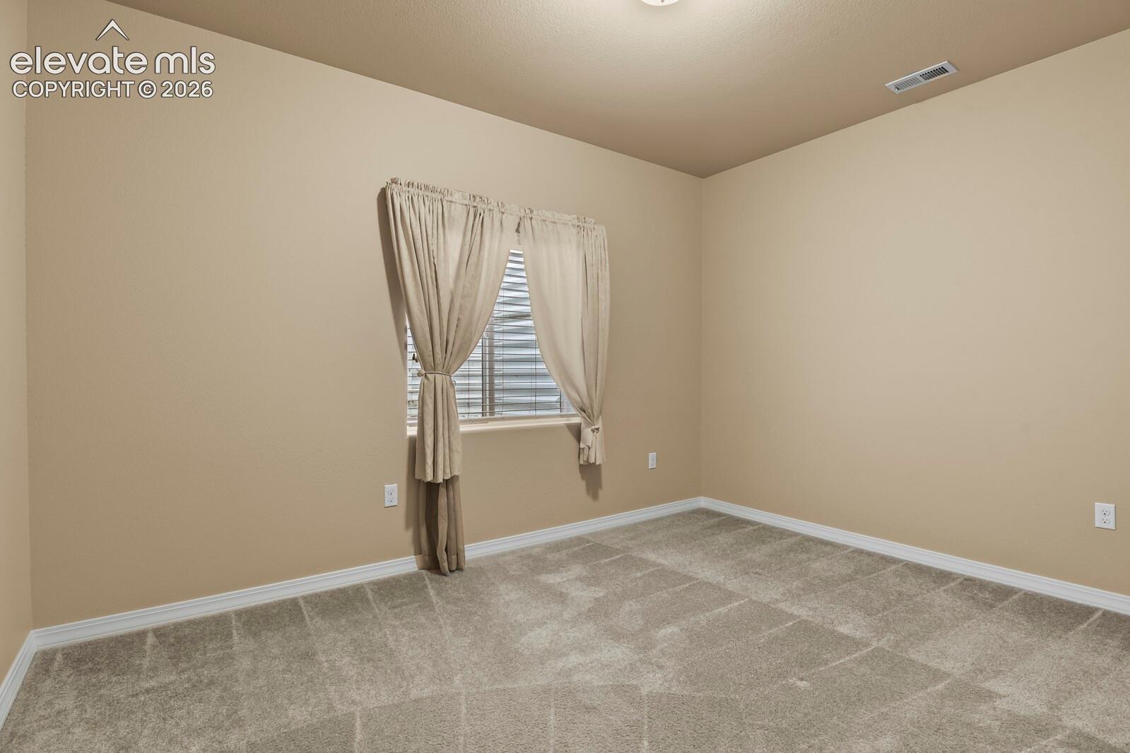 Neutral tone walls, grey carpeting, and a window with horizontal blinds