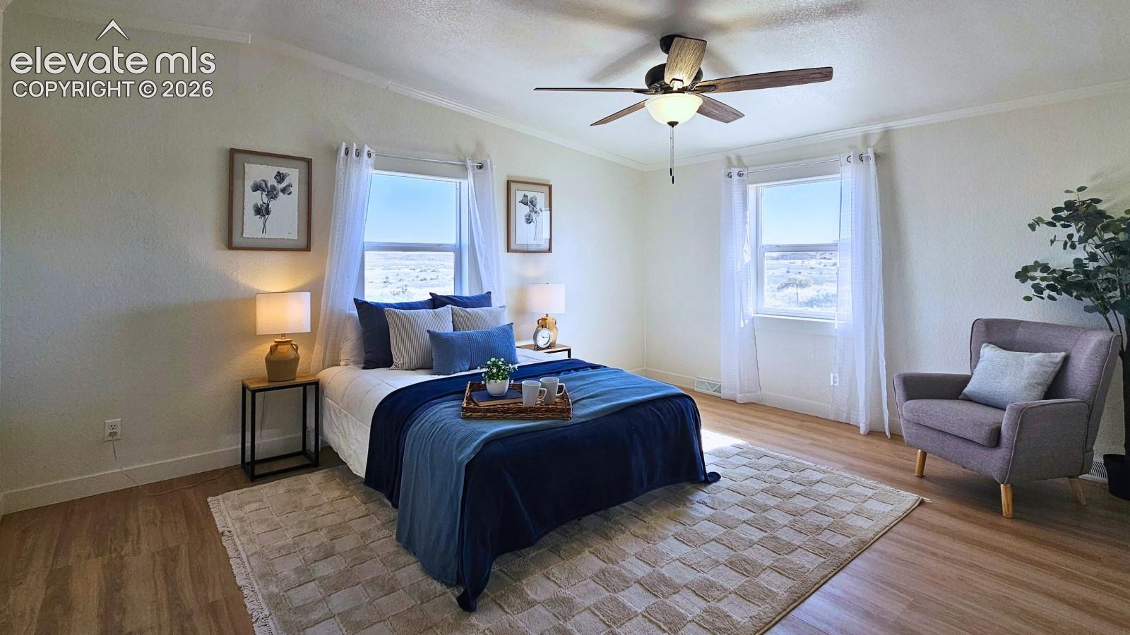 Room featuring wood-finish flooring, dual windows with natural light, and a ceiling fan with integrated lighting