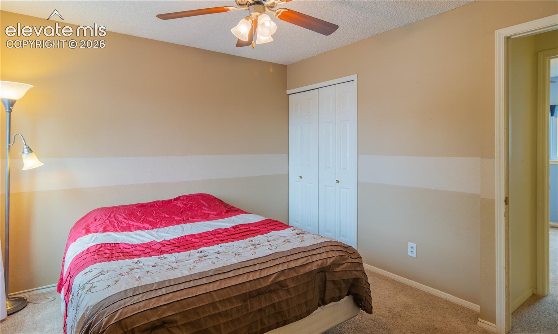 Carpeted room featuring a ceiling fan with light fixture and bifold closet doors