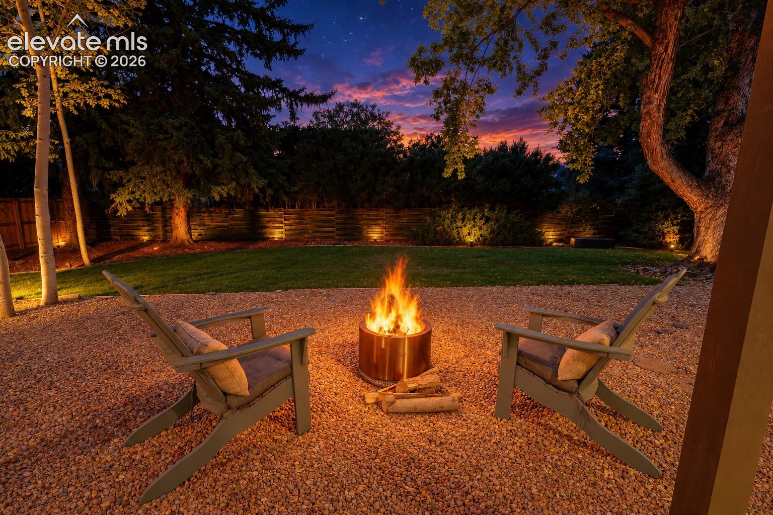 Gravel patio featuring a fire pit, surrounded by a manicured lawn and mature trees, with integrated landscape lighting