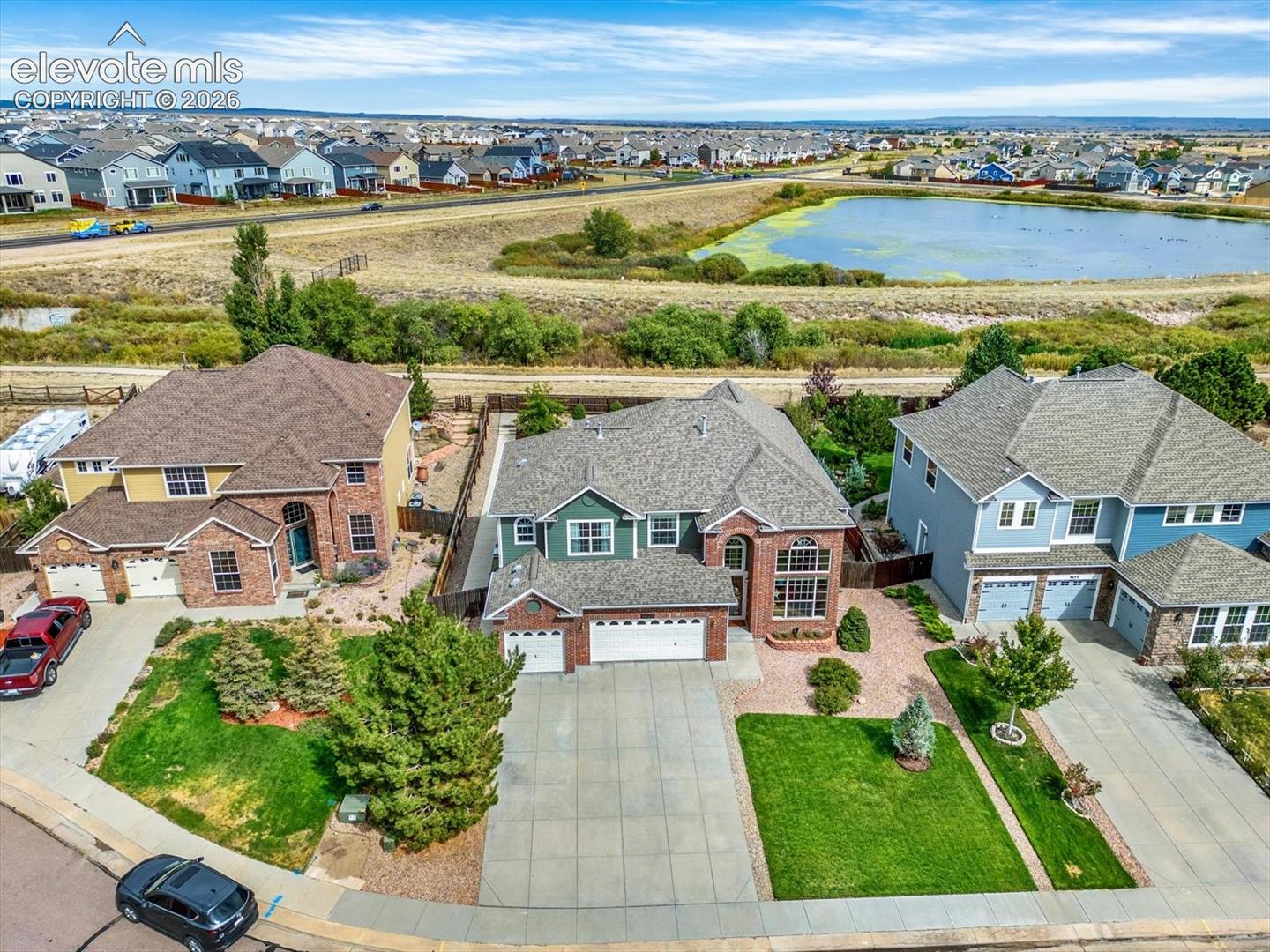 Two-story residence featuring brick and siding exterior, multi-gabled roofline, concrete driveway, attached three-car garage, and front yard landscaping